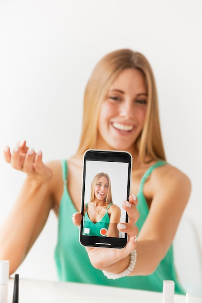 Front view female recording herself with mobile