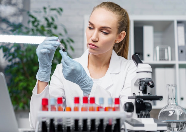 Front view of female researcher in the laboratory with test tubes and microscope