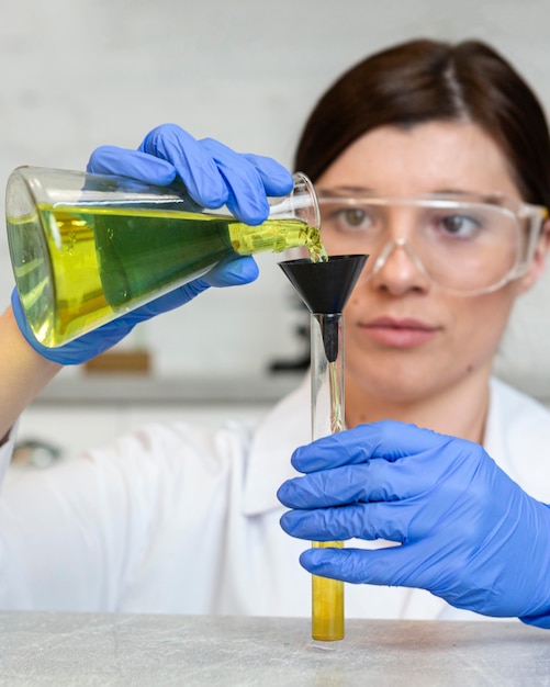 Front view of female researcher with safety glasses holding test tubes