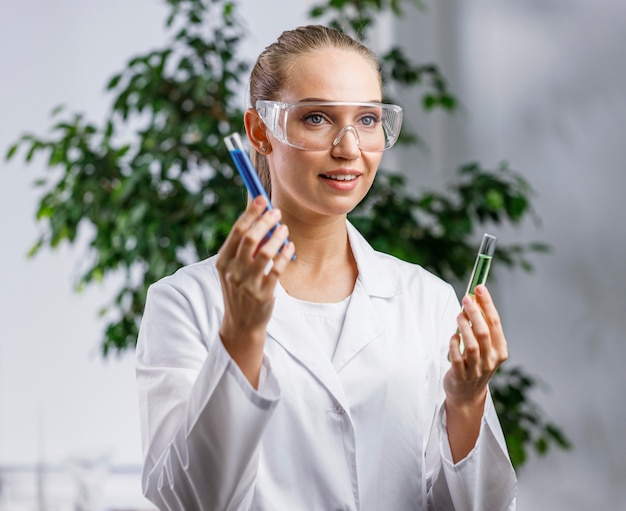 Free photo front view of female researcher with test tube and safety glasses