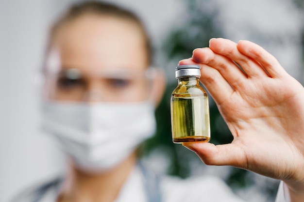 Front view of female researcher with vaccine bottle