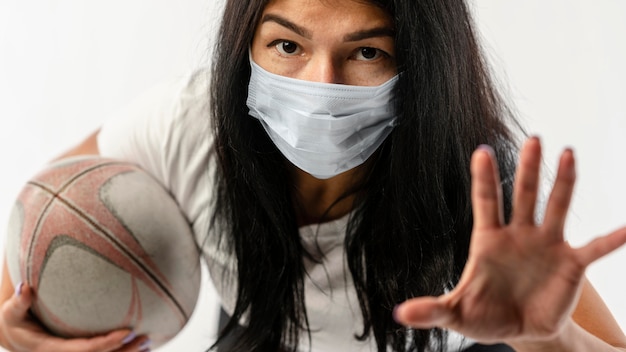 Foto gratuita vista frontale del giocatore di rugby femminile con maschera medica e palla