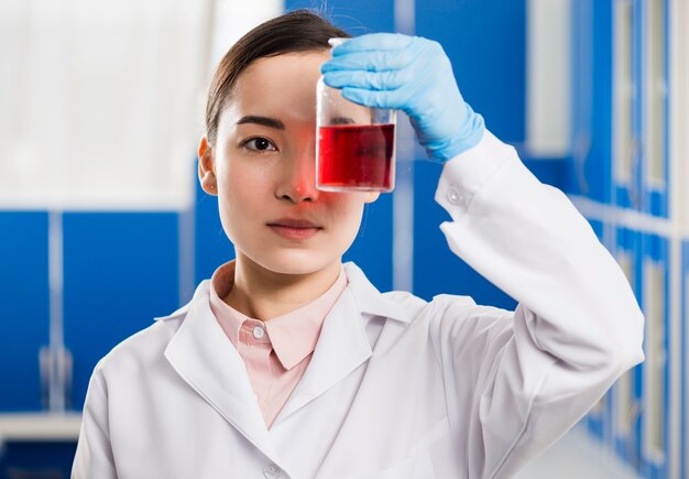 Вид спереди женского ученого, глядя на вещество лаборатории