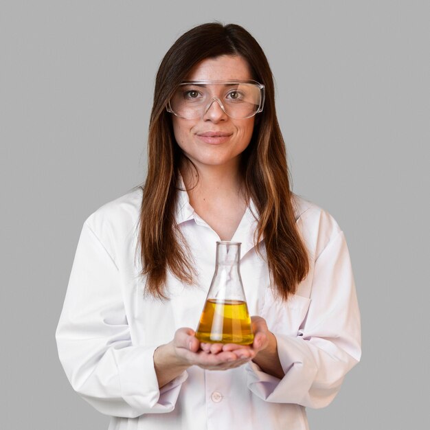 Front view of female scientist with safety glasses holding test tube