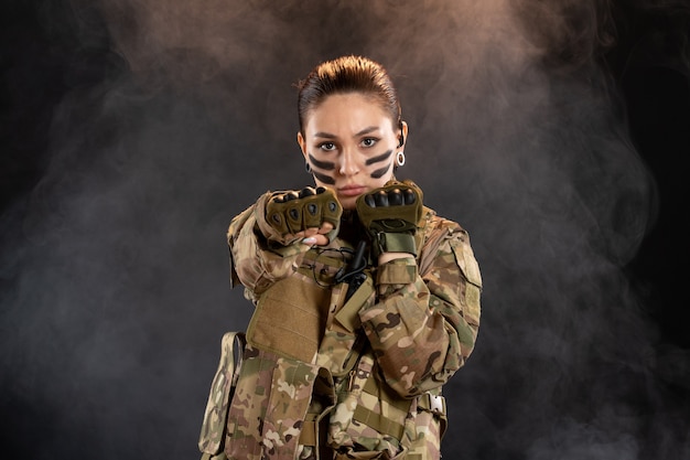 Front view of female soldier in camouflage black smoky wall