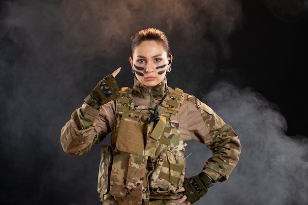 Free photo front view of female soldier in camouflage black smoky wall