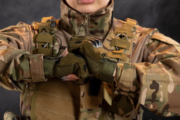 Front view of female soldier in camouflage on dark wall