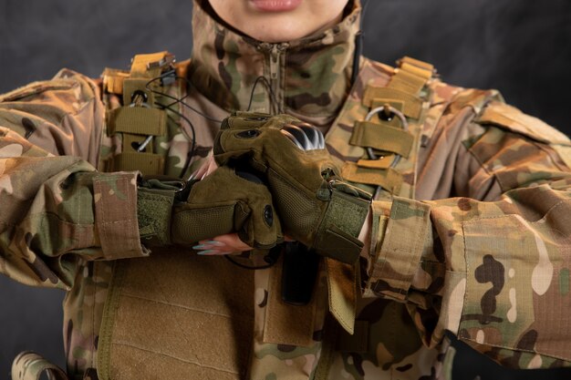 Front view of female soldier in camouflage on dark wall