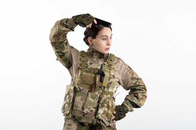 Front view female soldier in camouflage with gun on white wall