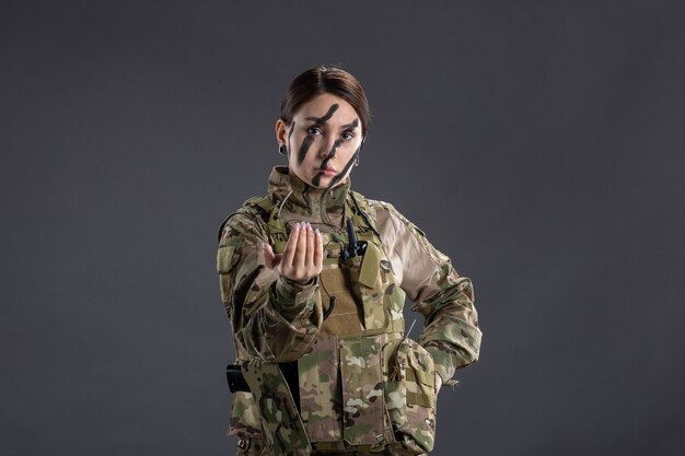 Front view of female soldier in military uniform on a dark wall