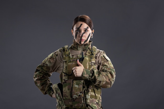 Front view of female soldier in military uniform on dark wall