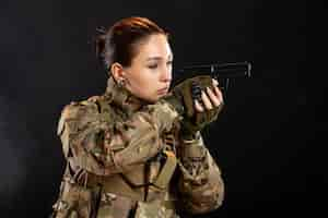 Foto gratuita vista frontale della soldatessa con la pistola in studio uniforme sulla parete nera