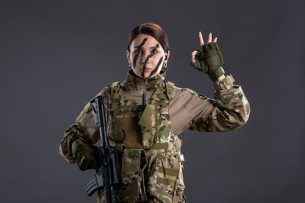 Free photo front view female soldier with machine gun in camouflage dark wall