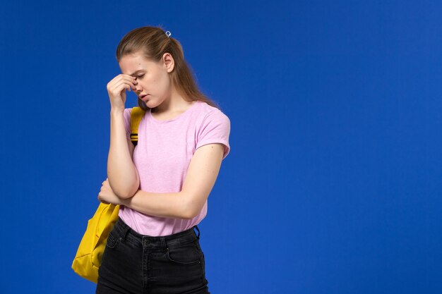 青い壁に黄色のバックパック落ち込んでいる女の子とピンクのTシャツの女子学生の正面図