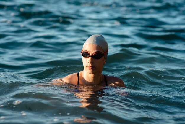 Front view of female swimmer with cap and goggles swimming in water