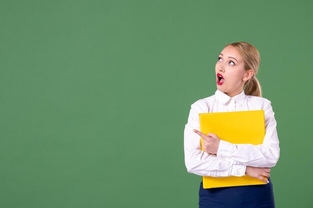 Front view female teacher holding yellow files on green background book study library school work university woman uniform student