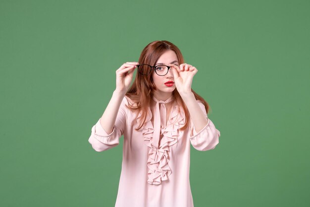 Front view female teacher in pink blouse on green background college color work book student job library lesson young school woman