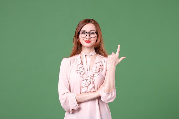 Front view female teacher in pink blouse on green background library college lesson work book student job young woman color