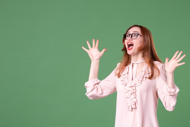 Front view female teacher in pink blouse looking above on green