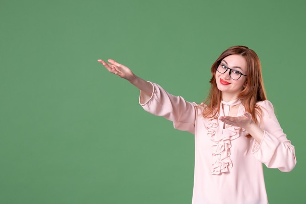 Front view female teacher in pink blouse pointing at something on green