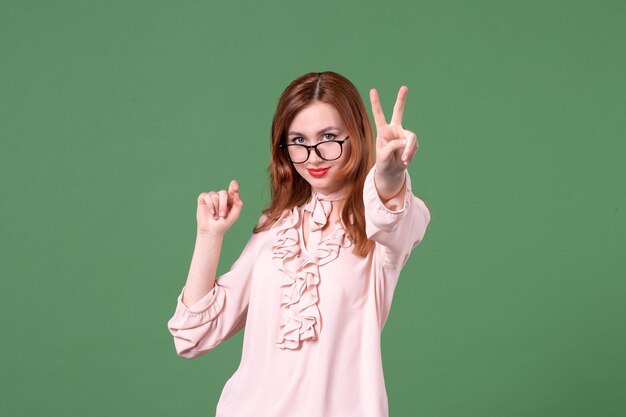 Insegnante femminile di vista frontale in camicetta rosa che posa sul verde