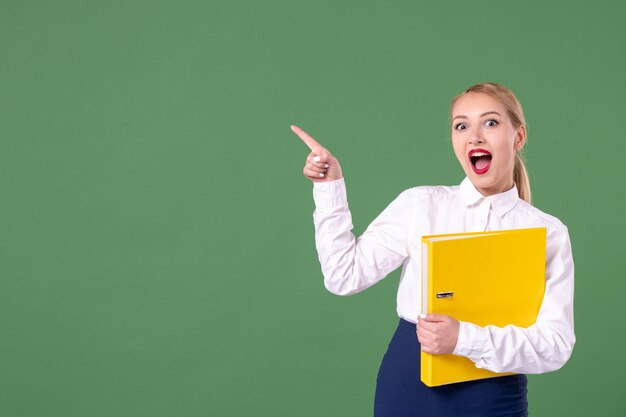 Front view female teacher with yellow files on green background lesson work student university study uniform woman school book