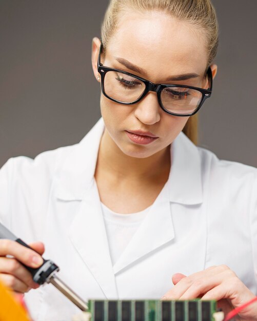 Front view of female technician with electronics and soldering iron