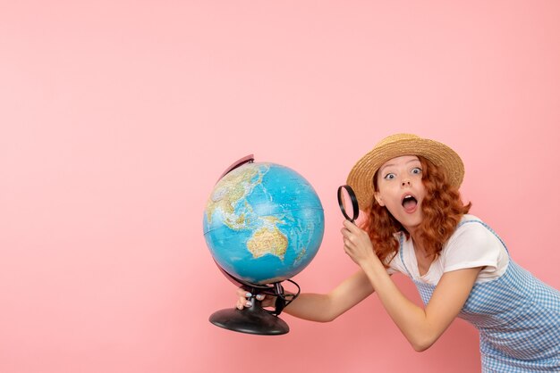 Front view female tourist exploring globe with magnifier