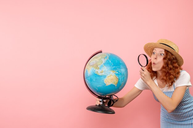 Front view female tourist exploring globe with magnifier