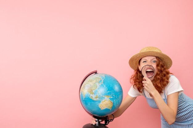 Женщина-туристка, изучающая земной шар с лупой, вид спереди