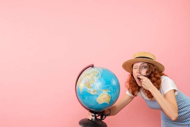 Front view female tourist exploring globe with magnifier