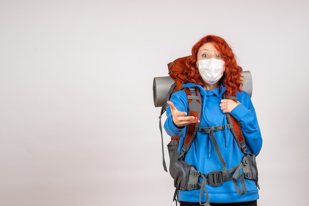 Бесплатное фото Вид спереди туристка, идущая в горное путешествие в маске с рюкзаком