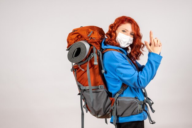 Front view female tourist going in mountain trip in mask with backpack posing