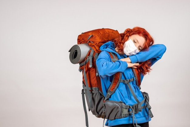 Free photo front view female tourist going in mountain trip in mask with backpack tired