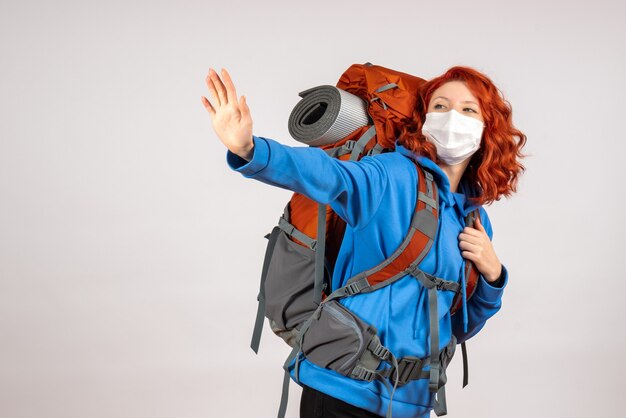 Front view female tourist going in mountain trip in mask with backpack