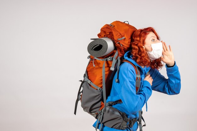 バックパックとマスクで山の旅に行く女性観光客の正面図