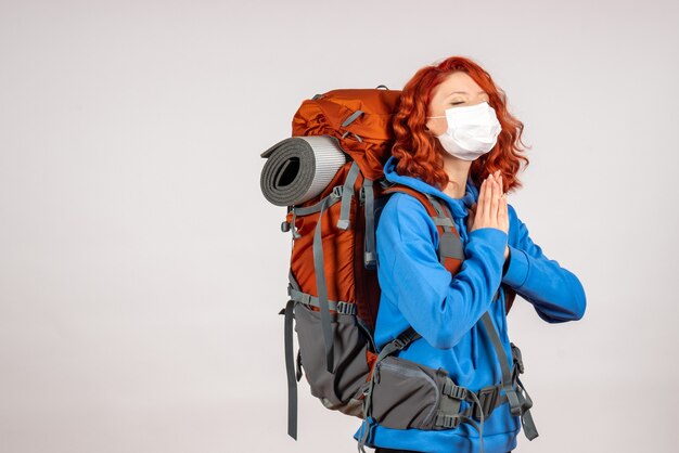 Front view female tourist going in mountain trip in mask with backpack