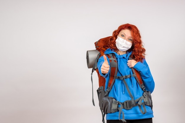 Free photo front view female tourist going in mountain trip in mask with backpack