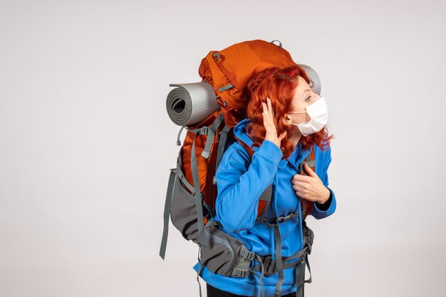 Front view female tourist going in mountain trip in mask with backpack