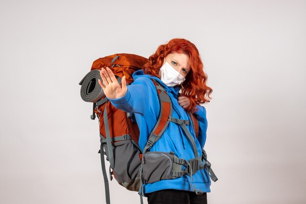 Вид спереди туристка, идущая в горное путешествие в маске с рюкзаком