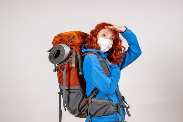 Front view female tourist going in mountain trip in mask with backpack