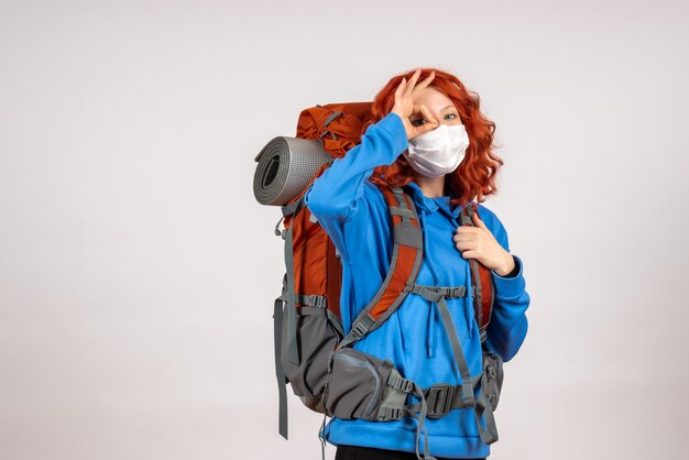 Вид спереди туристка, идущая в горное путешествие в маске с рюкзаком