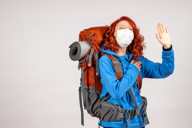 バックパックとマスクで山の旅に行く女性観光客の正面図