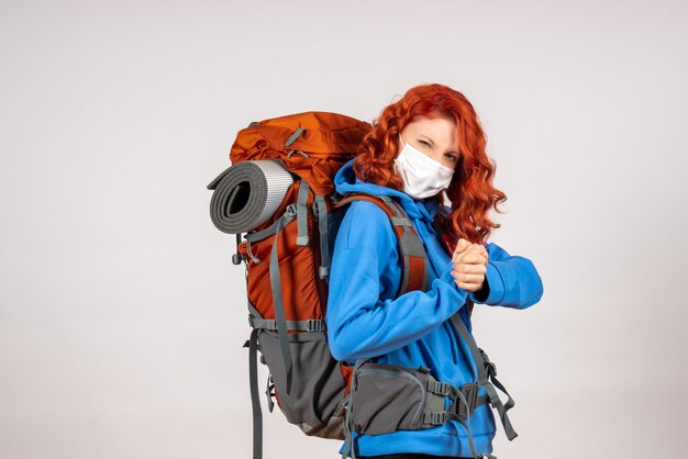 Front view female tourist going in mountain trip in mask with backpack