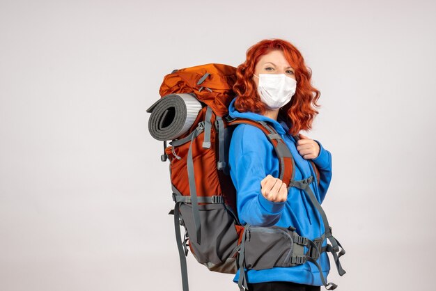 Front view female tourist going in mountain trip in mask with backpack