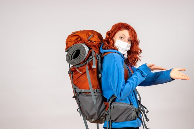 Front view female tourist going in mountain trip in mask with backpack