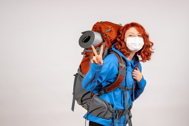 Front view female tourist going in mountain trip in mask with backpack