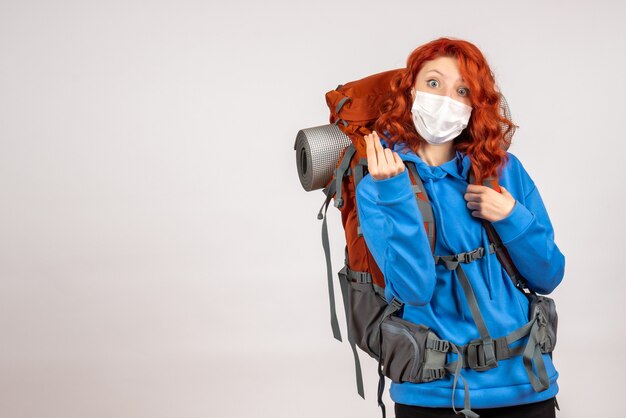 Front view female tourist going in mountain trip in mask with backpack