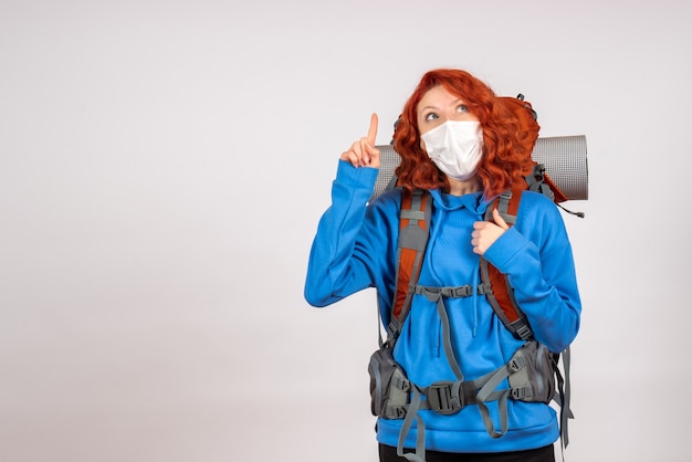 Front view female tourist going in mountain trip in mask with backpack