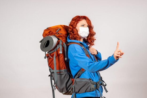 Front view female tourist going in mountain trip in mask with backpack